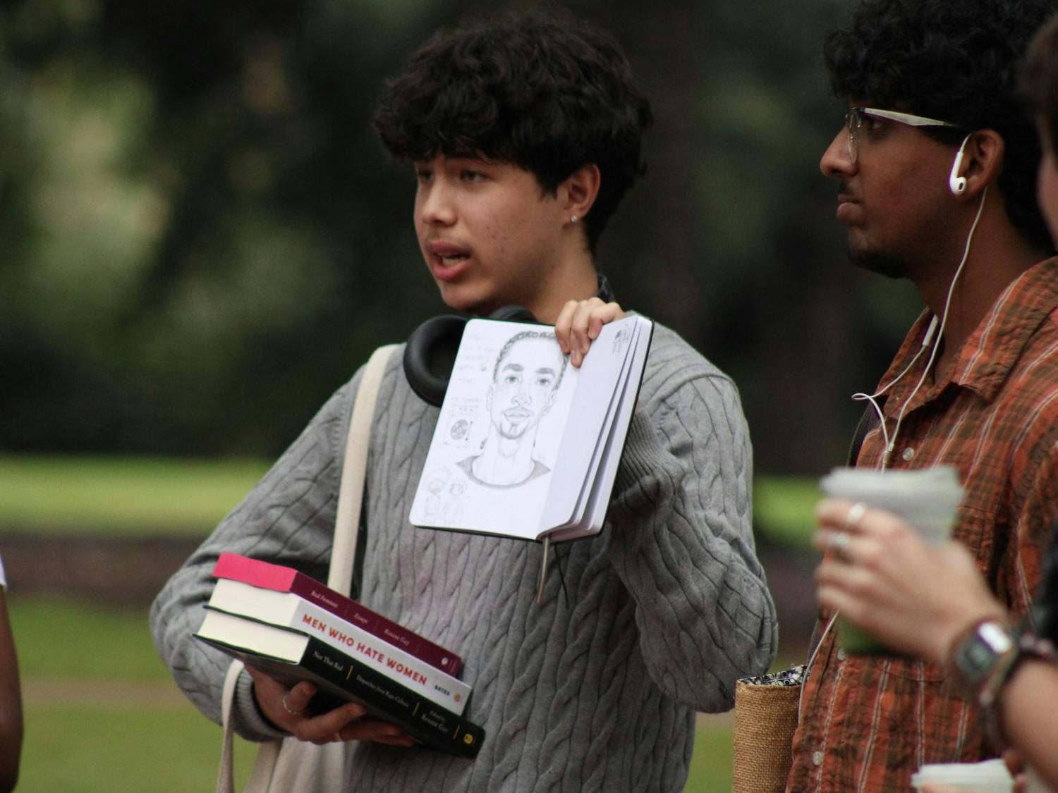 A contestant in the Performative Male Contest, presents a drawing as part of his presentation. He is one of many students who are competing in the event.