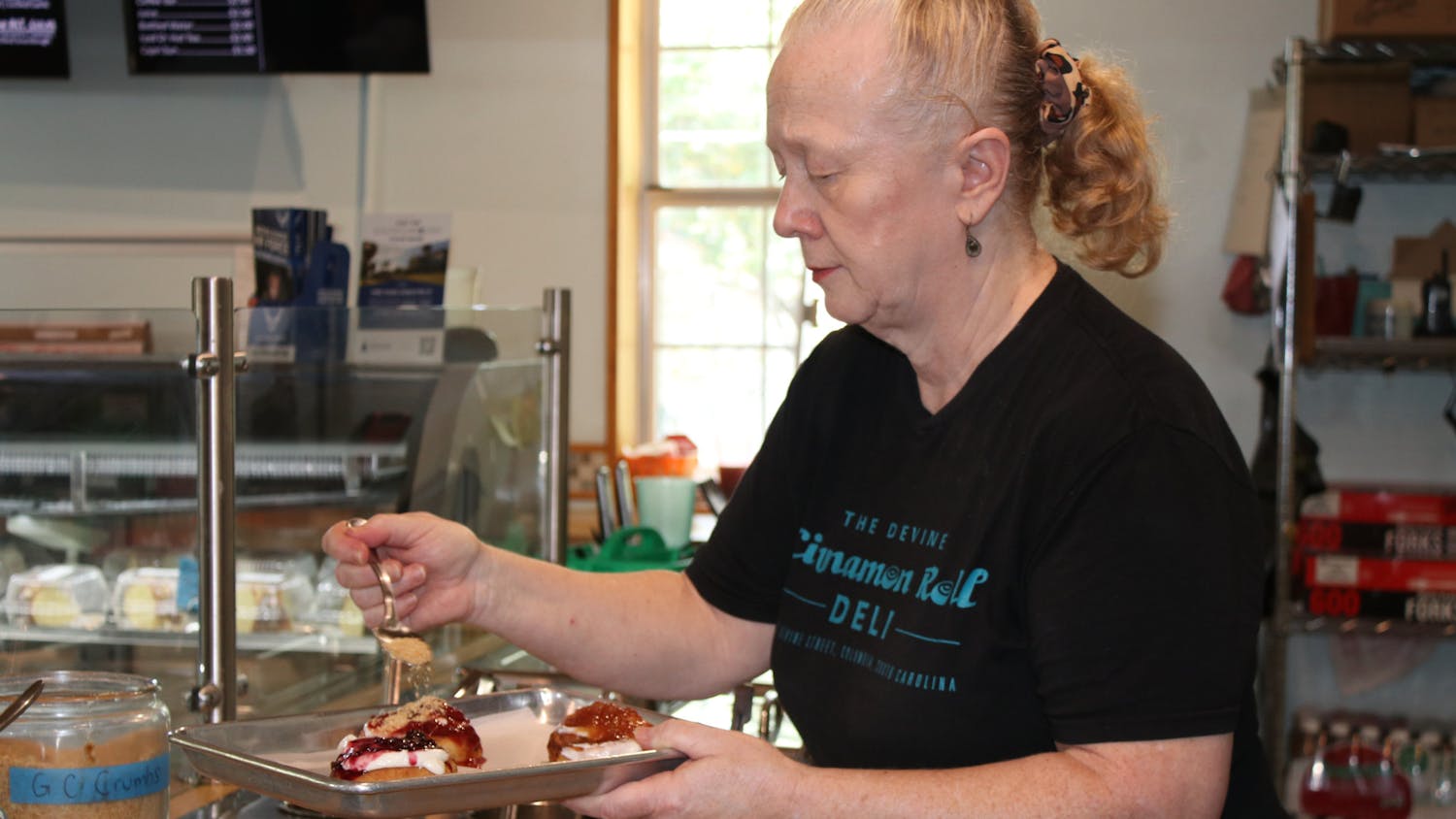 The Devine Cinnamon Roll Deli owner Jody Kreush puts toppings on a few of the restaurants in-house cinnamon rolls on Sept. 6, 2023. The 'breakfast joint' has been featured on Food Network, Southern Living and more.