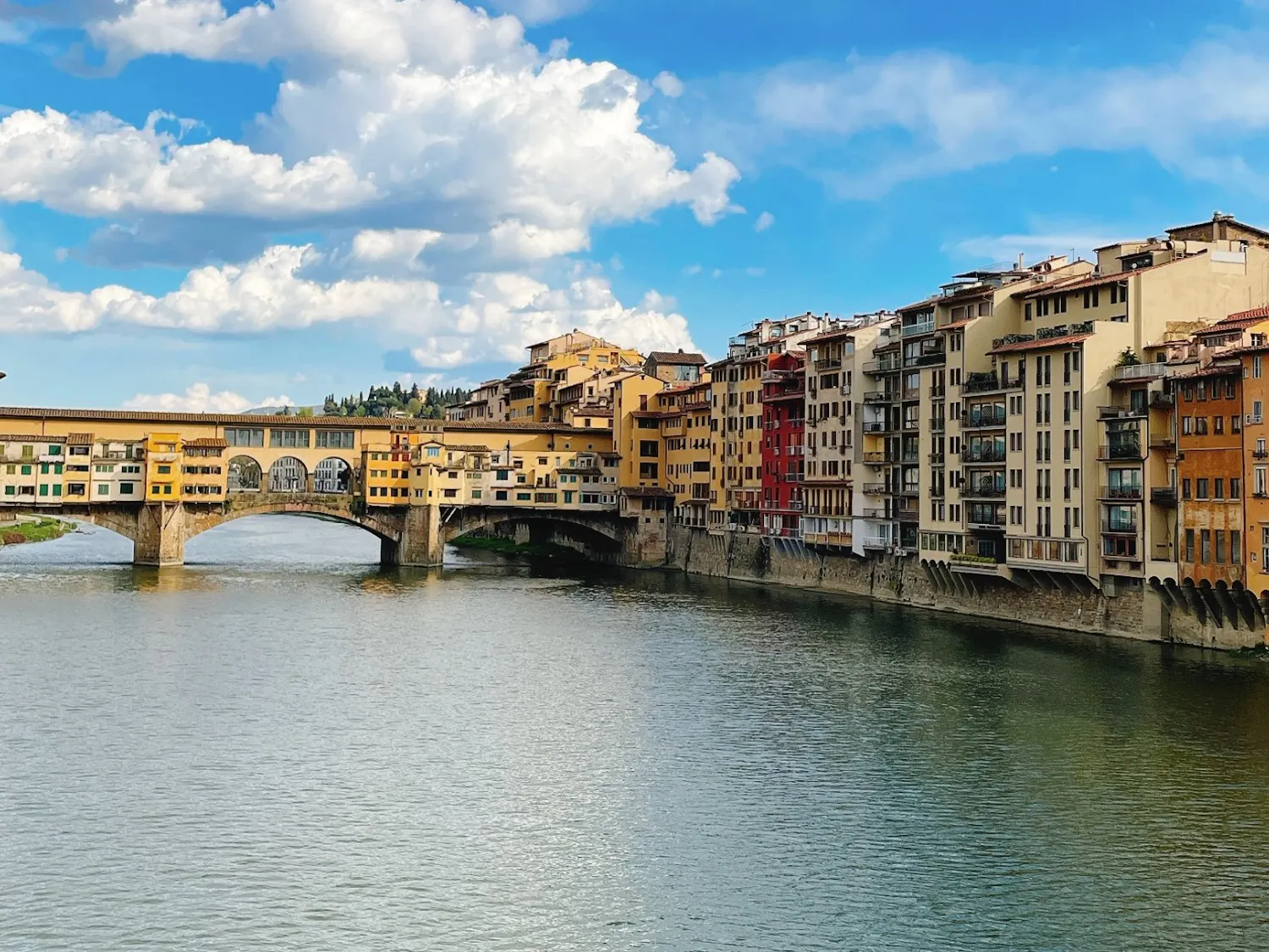 A canal in Florence, Italy, that is faced by buildings on each side and has a bridge to let pedestrians cross the canal. 