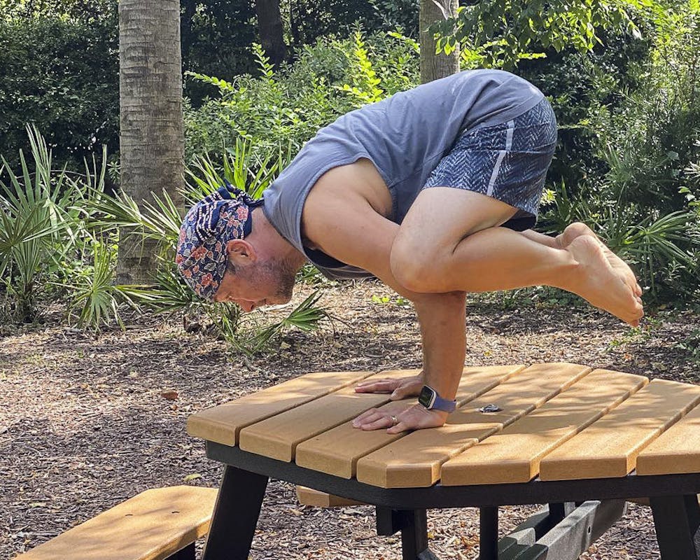 <p>David Moscowitz, a professor at the School of Journalism and Mass Communications stands in the Bakasana yoga pose, a.k.a. the Crow Pose. Moscowitz offers donation-funded yoga lessons at Rooted Yoga, on Sunday afternoons.&nbsp;</p>