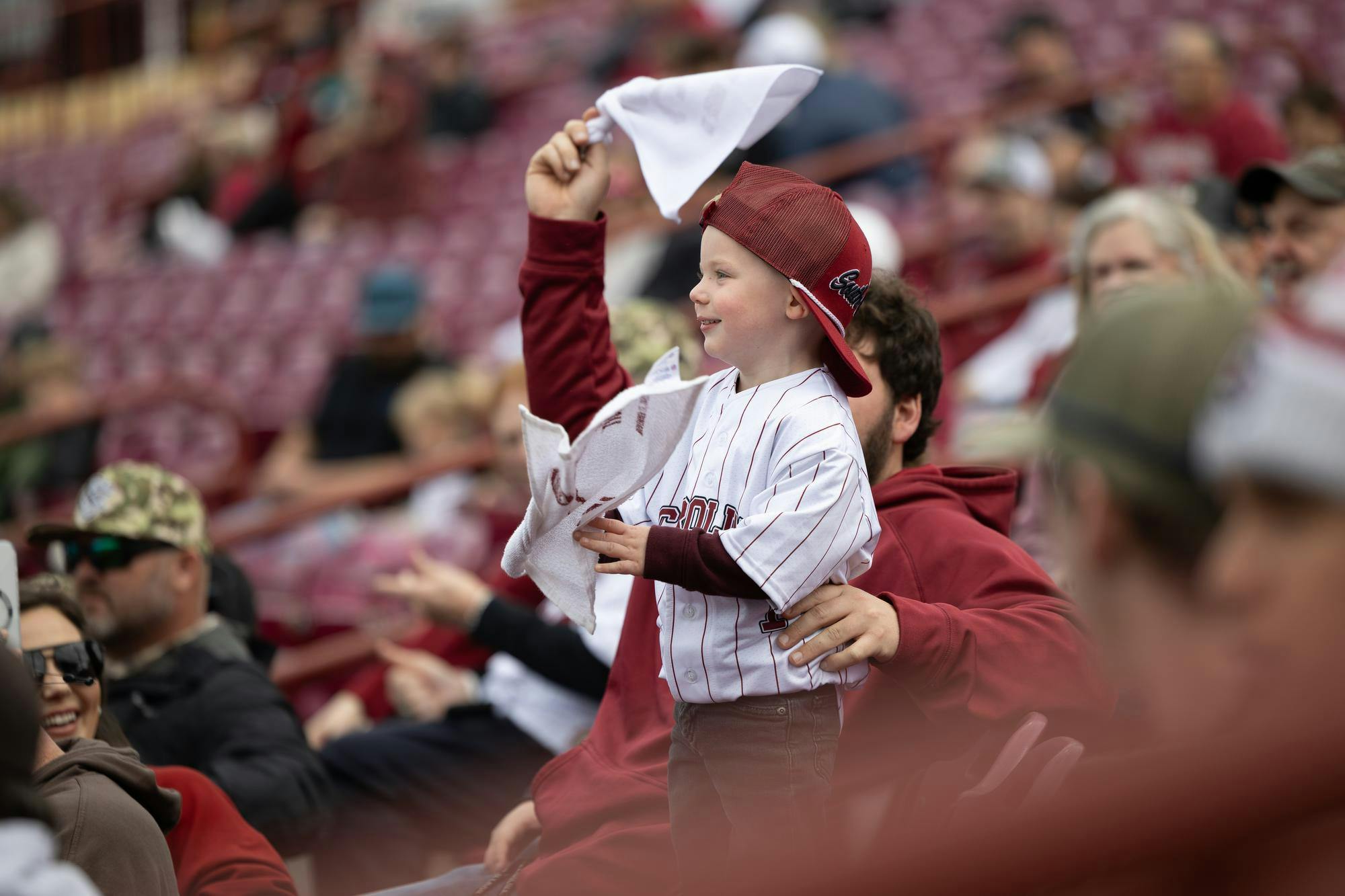 A young Gamecock baseball fan sandstorms with their parent in Founder's Park on Feb. 16, 2025 to celebrate a Gamecock home run. Sandstorm serves as a celebraroty tradition in athletics at the University of South Carolina.