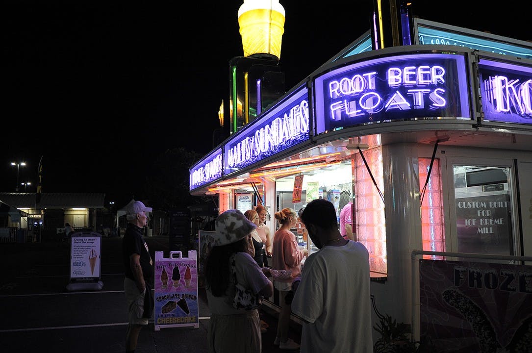 People attending the fair line up at a food stand that serves root beer floats and ice cream.&nbsp;