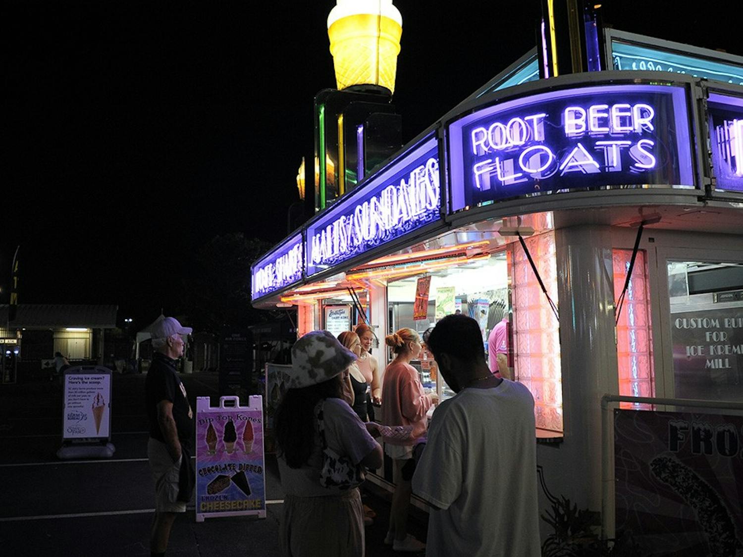 People attending the fair line up at a food stand that serves root beer floats and ice cream.&nbsp;