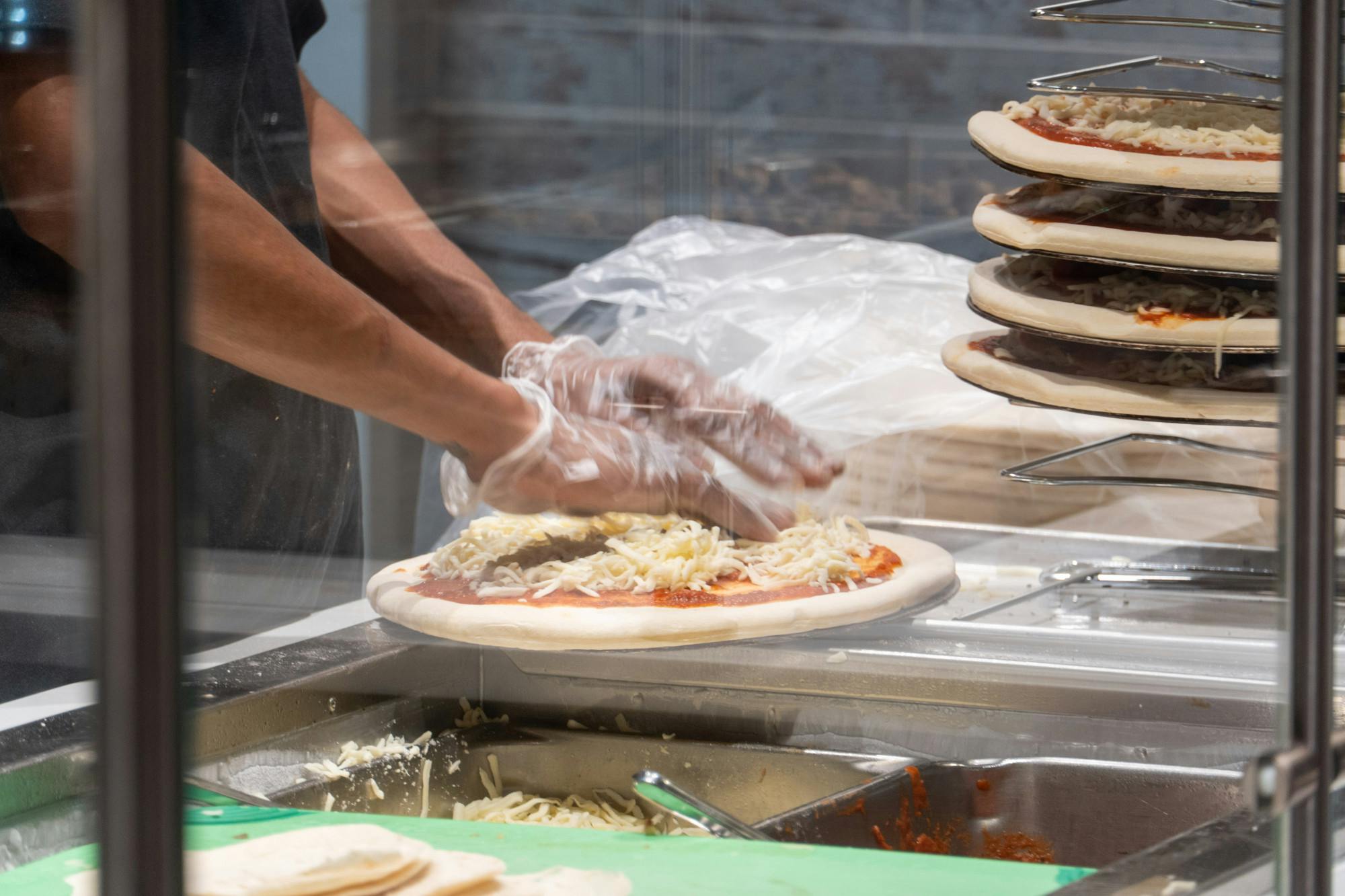 A worker preps a pizza at Fresh Greene's pizza station on Sept. 20, 2022. Fresh Greene's, an organic buffet style eatery located in Russell House, serves fresh a fresh and healthier alternative to the campus community.