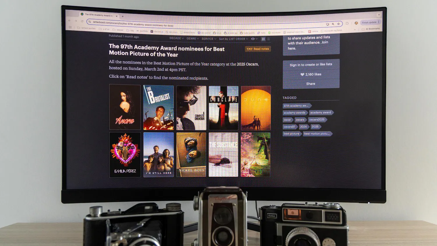 A monitor showing the Oscar nominees for Best Motion Picture of the Year sits on a desk with vintage cameras. The 97th Academy Awards will be broadcasted on March 2, 2025 at 7 p.m. EST.