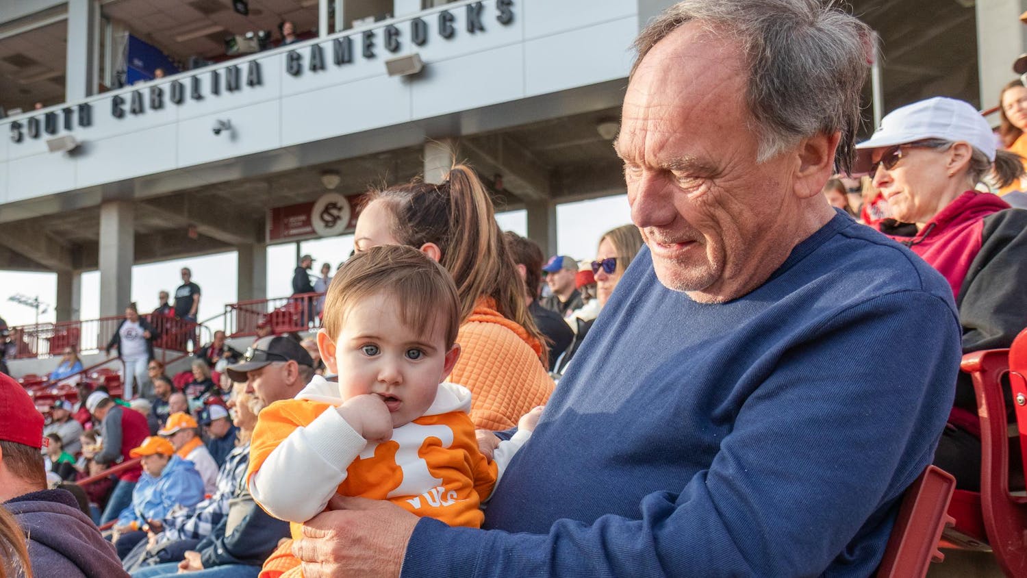 Young University of Tennessee fan Kellam Knox Edwards, 9 months, stares at the camera during the matchup against the University of South Carolina at Beckham Field on March 24, 2024. Kellam, his grandfather Chuck Edwards (right) and his mother Lauren Edwards are from North Carolina and travel to many of the Volunteers' games.