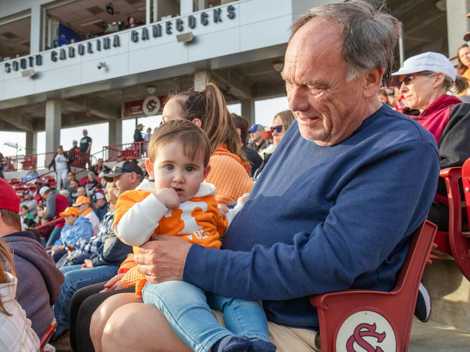 Young University of Tennessee fan Kellam Knox Edwards, 9 months, stares at the camera during the matchup against the University of South Carolina at Beckham Field on March 24, 2024. Kellam, his grandfather Chuck Edwards (right) and his mother Lauren Edwards are from North Carolina and travel to many of the Volunteers' games.