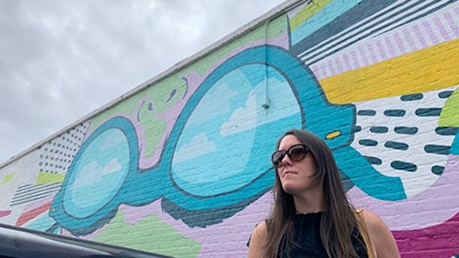 Freelance artist Cait Maloney stands in front of her mural "Lady Vista" located on the wall of Boku Kitchen and Saloon in Columbia, SC.
