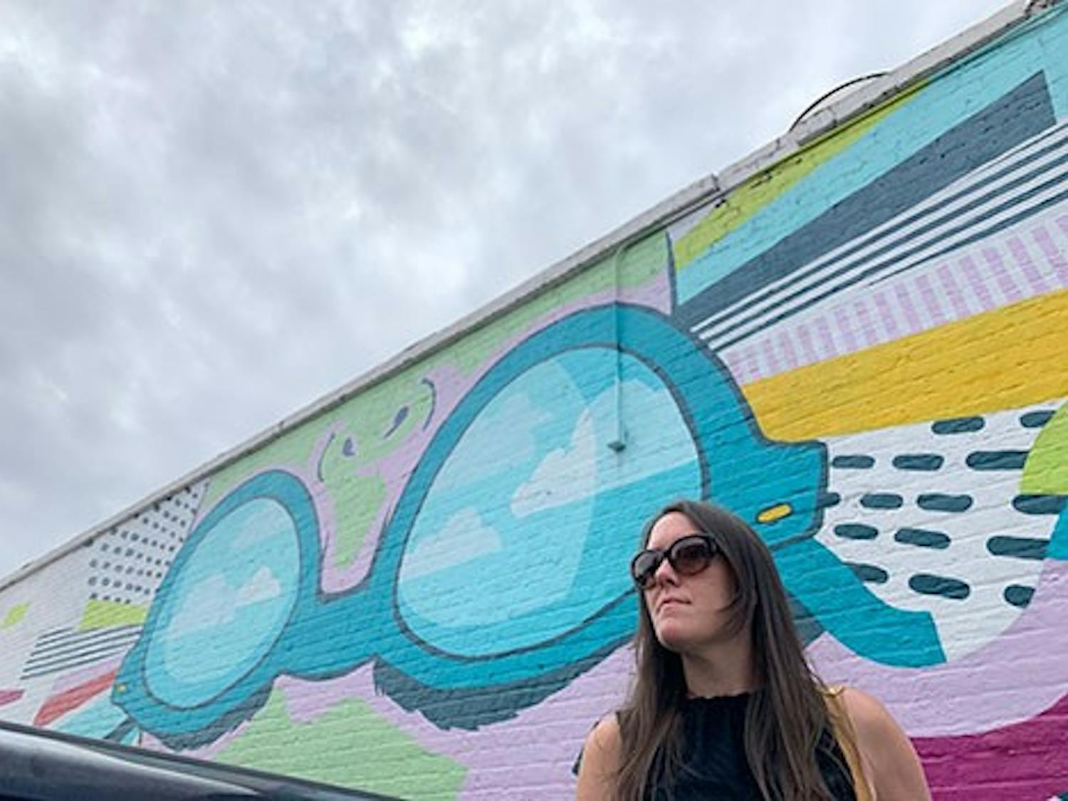 Freelance artist Cait Maloney stands in front of her mural "Lady Vista" located on the wall of Boku Kitchen and Saloon in Columbia, SC.