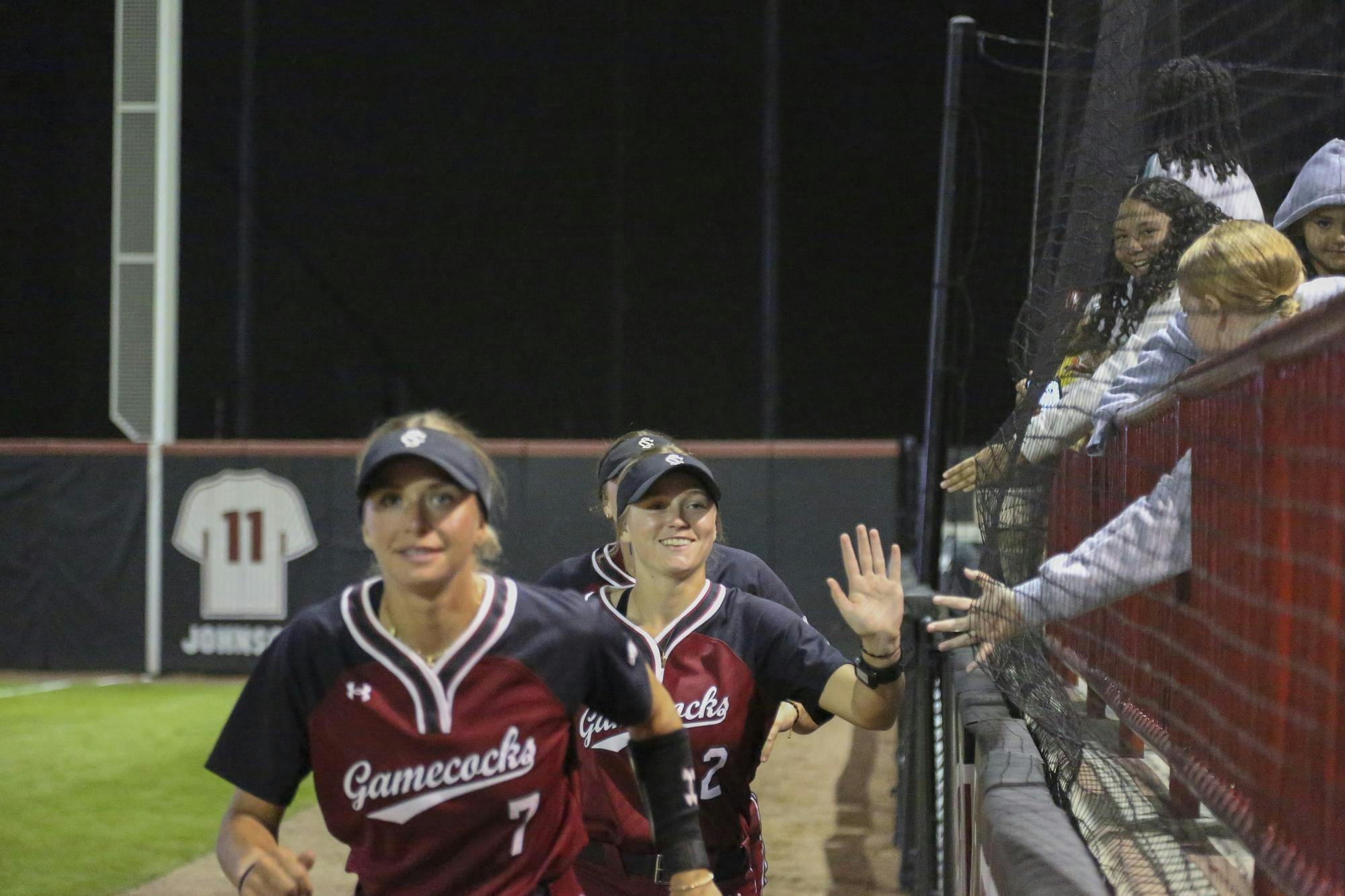 Kids in the stadium reach out their hands for a high-five from members of the USC women’s softball team at the game against Furman at the Carolina Softball Stadium on Oct. 17, 2025. Many people came to watch the game and have a good time cheering their team on.