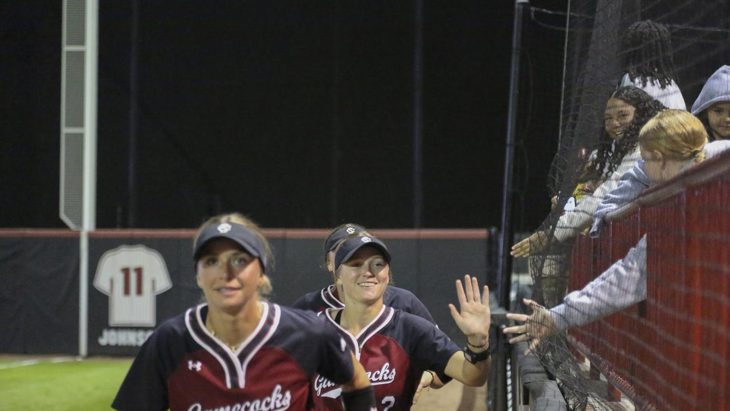 Kids in the stadium reach out their hands for a high-five from members of the USC women’s softball team at the game against Furman at the Carolina Softball Stadium on Oct. 17, 2025. Many people came to watch the game and have a good time cheering their team on.