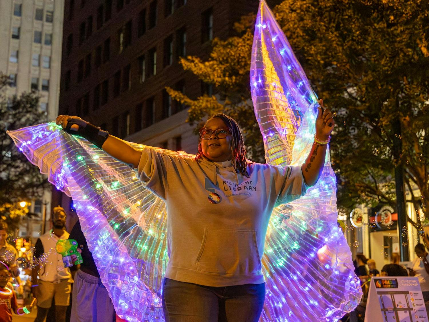 A woman with the Richland County Library waves a rainbow light-up banner during the parade at the first night of the Famously Hot SC Pride Festival on Oct. 3, 2025. The marchers paraded down Main Street towards the Smirnoff Main Stage at the intersection of Lady Street.