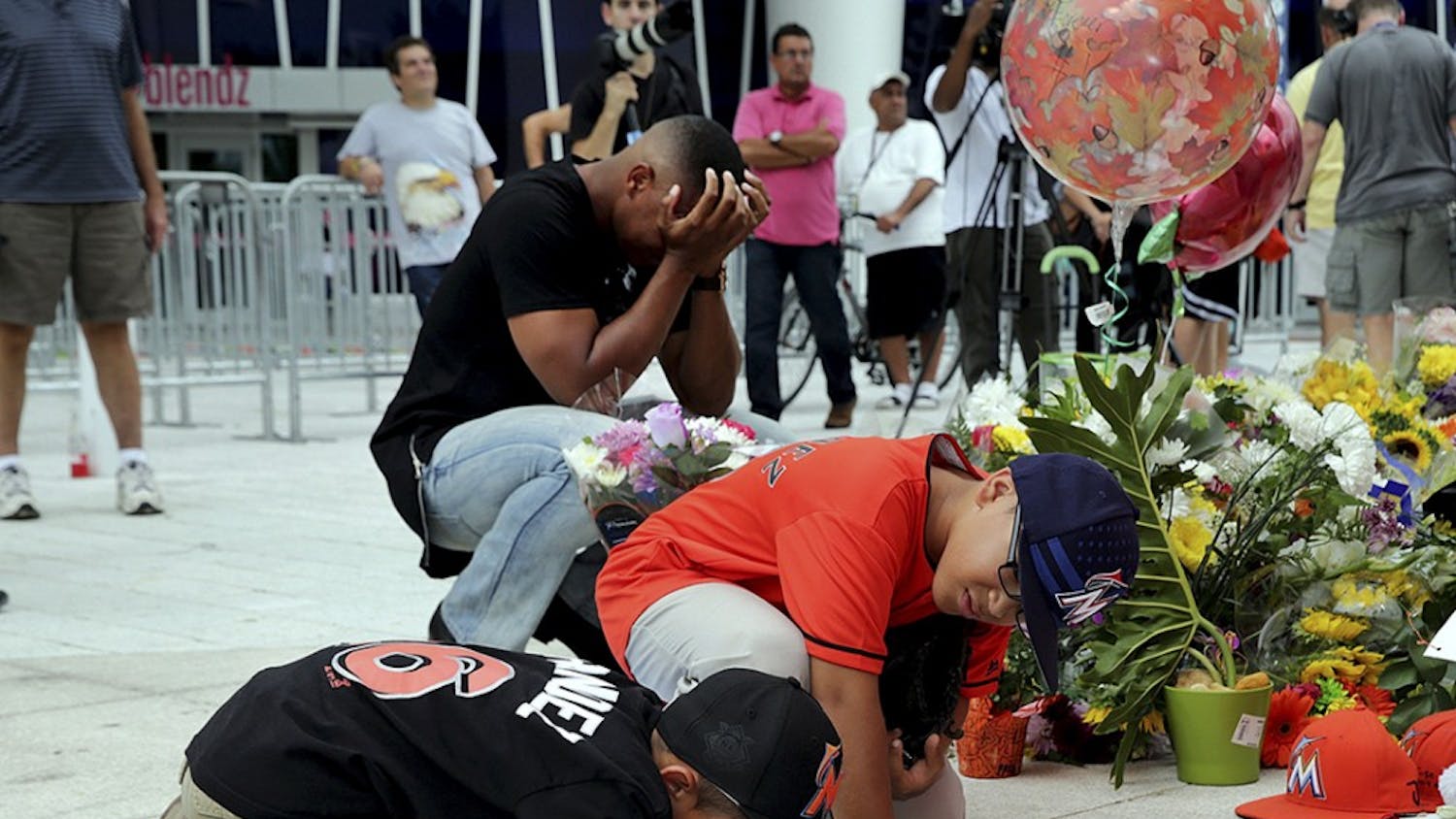 Fans Peyton Holton (front) and Shawn Lopez pay tribute by signing posters at a memorial for Miami Marlins' pitcher Jose Fernandez, who died on a boat accident Sunday morning, on Monday, Sept. 26, 2016 at Marlins Park in Miami, Fla. (Pedro Portal/Miami Herald/TNS)