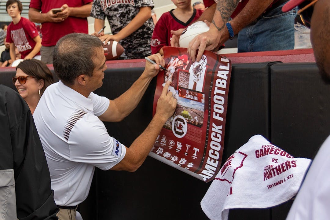FILE— South Carolina football head coach Shane Beamer signing a football poster before taking on Eastern Illinois on Sept. 4, 2021.