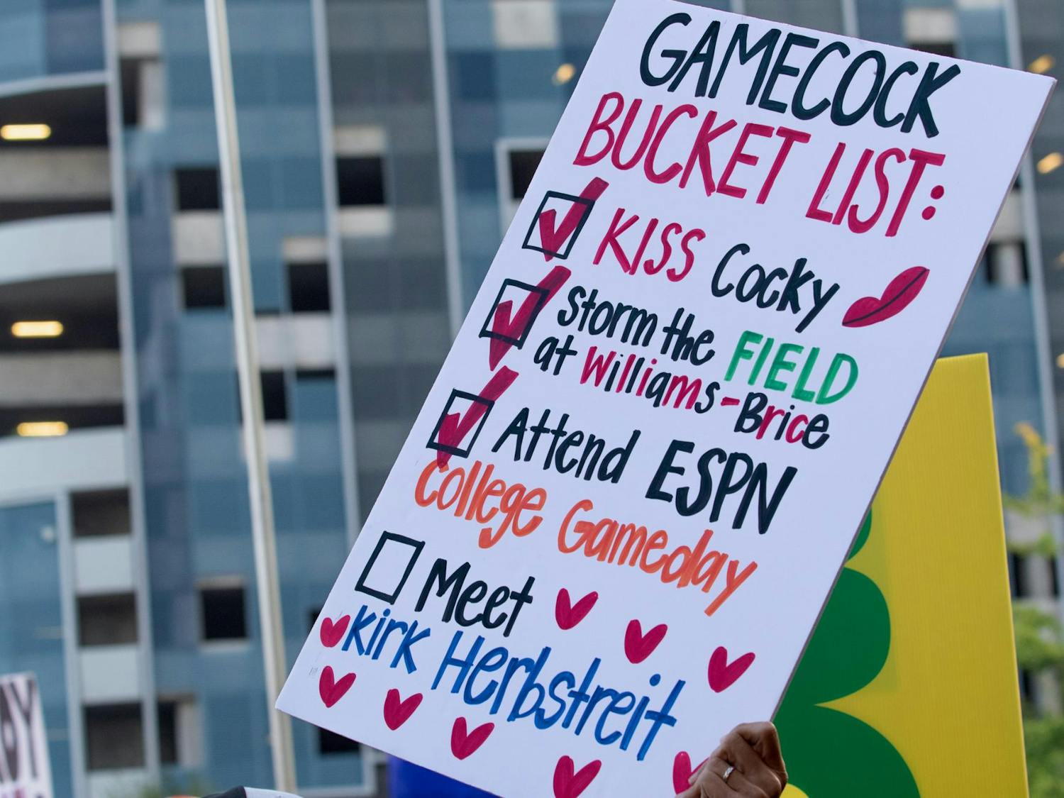 A fan holds up a sign of her “Gamecock Bucket List”. Thousands of South Carolina and North Carolina fans gathered to cheer for their teams during ESPN’s College GameDay broadcast ahead of the neutral site game.