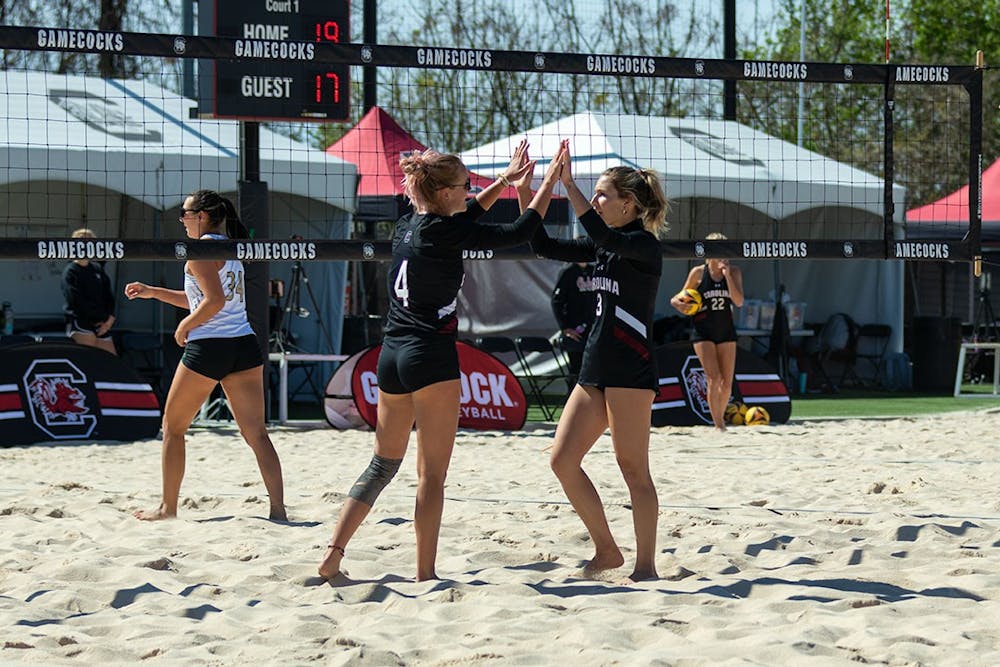 <p>Junior Hailey Cabeceiras and junior Sophie Manson congratulate each other after a point at Wheeler Beach on April 2, 2022. South Carolina won three out of for games in the Carolina Challenger.</p>
