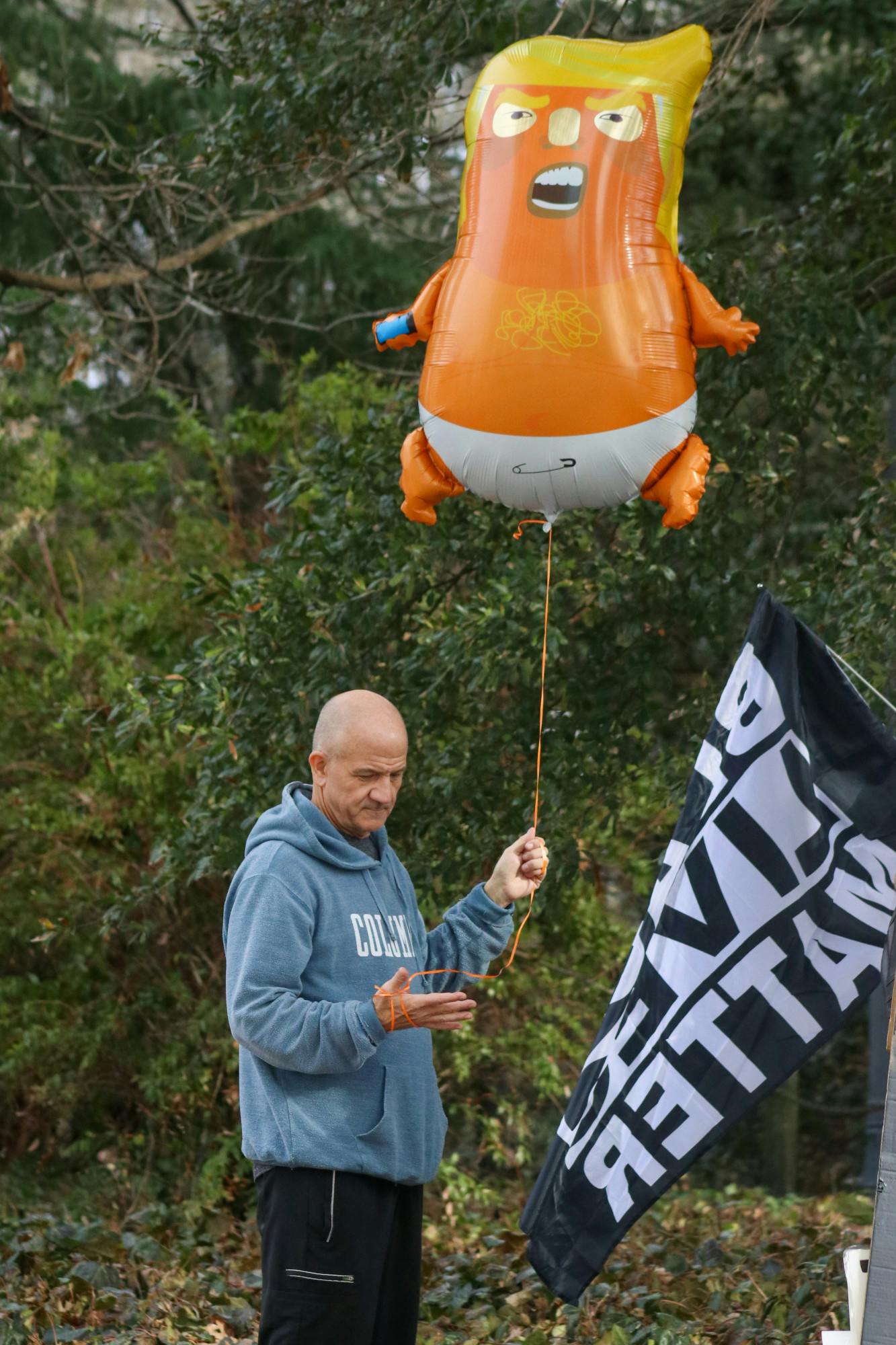 A man holds a Trump-looking balloon outside of the Statehouse on Jan. 28, 2023. A small group of regular Ben Tillman statue protestors added anti-Trump rhetoric to their usual sidewalk presence. They remained peaceful even as police officers removed them from their spot for blocking off the walkway.&nbsp;