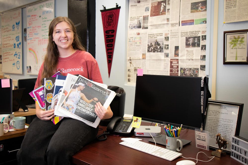 <p>The Editor-in-Chief of The Daily Gamecock, Sydney Dunlap, poses on her desk on Dec. 3, 2023, holding each print edition she worked on as editor-in-chief. Dunlap held this position for the spring and fall 2023 semesters.</p>