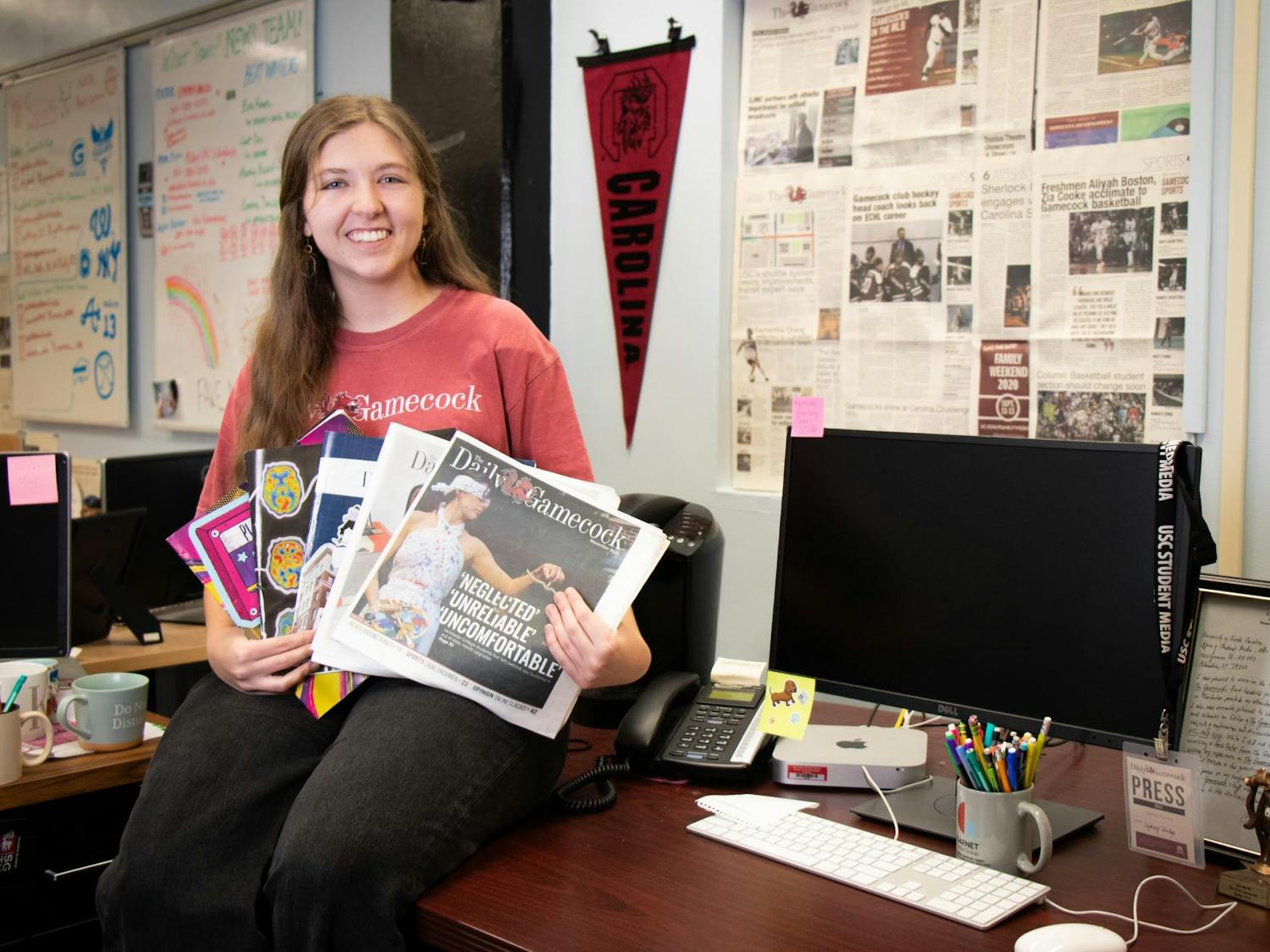 The Editor-in-Chief of The Daily Gamecock, Sydney Dunlap, poses on her desk on Dec. 3, 2023, holding each print edition she worked on as editor-in-chief. Dunlap held this position for the spring and fall 2023 semesters.