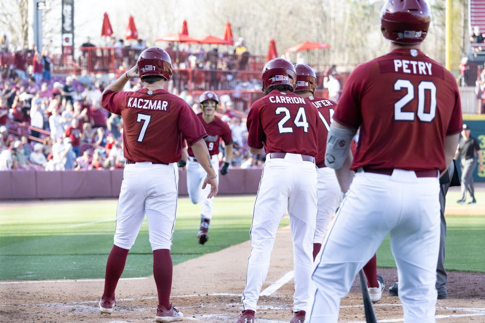 <p>Three University of South Carolina players await their teammates crossing home plate after scoring a run during their matchup against Morehead State at Founders Park on March 8, 2025. The Gamecocks won 16-11.</p>