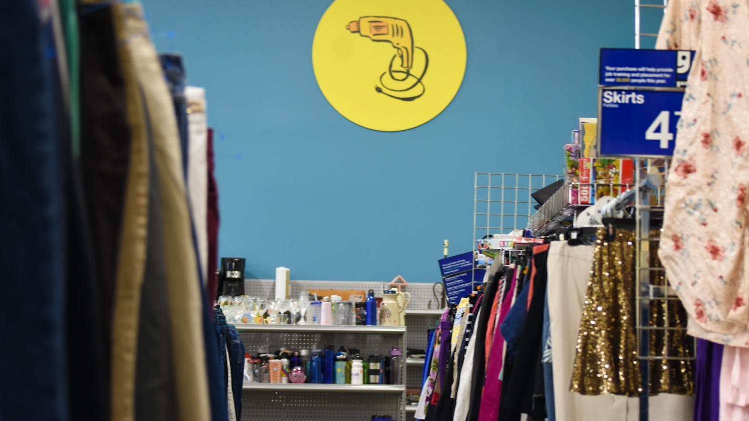 An aisle within a Goodwill retail store. The act of thrifting and the rise of secondhand-centered e-commerce apps have become popular among college students who seek to buy clothing at lower prices and combat unsustainable practices within the fashion industry.