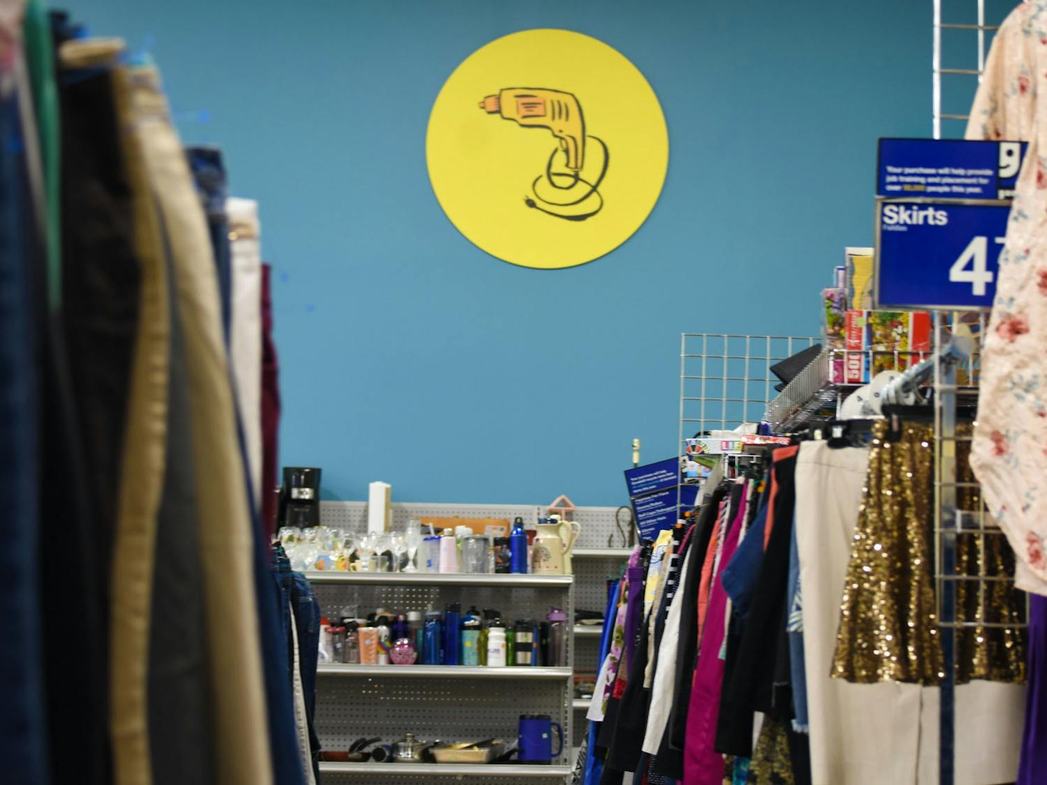 An aisle within a Goodwill retail store. The act of thrifting and the rise of secondhand-centered e-commerce apps have become popular among college students who seek to buy clothing at lower prices and combat unsustainable practices within the fashion industry.