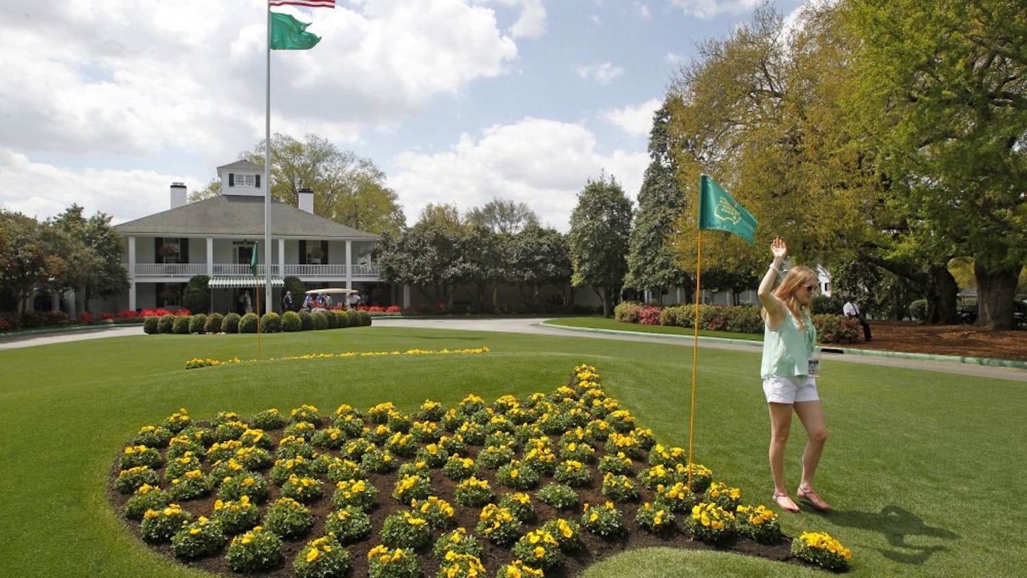 A patron poses for photos next to the Masters logo in flowers at Founders Circle in front of the Augusta National clubhouse in Augusta, Georgia, during a practice round for The Masters, Monday, April 8, 2013. (Gerry Melendez/The State/MCT)