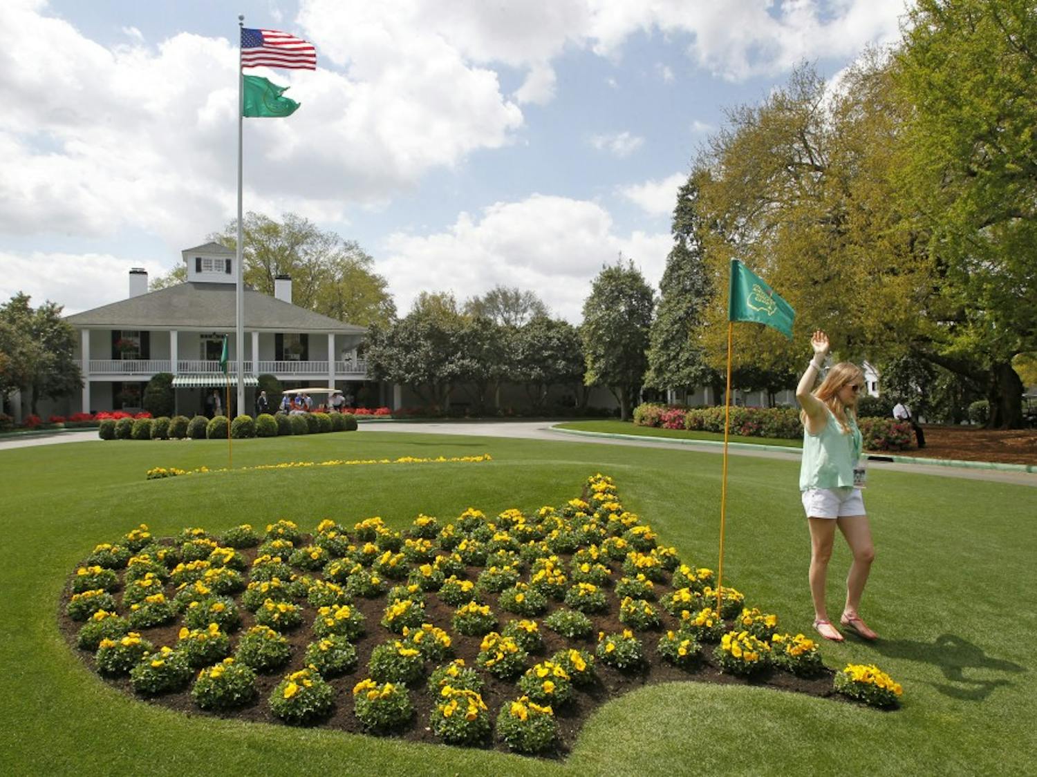 A patron poses for photos next to the Masters logo in flowers at Founders Circle in front of the Augusta National clubhouse in Augusta, Georgia, during a practice round for The Masters, Monday, April 8, 2013. (Gerry Melendez/The State/MCT)