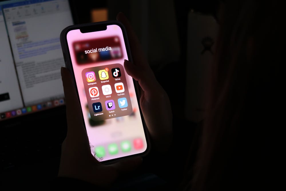 <p>A photo illustration of a student opening the popular social media app, TikTok, in her dorm on Feb. 5, 2023. USC announced that it's networks would no longer support TikTok earlier in August.</p>
