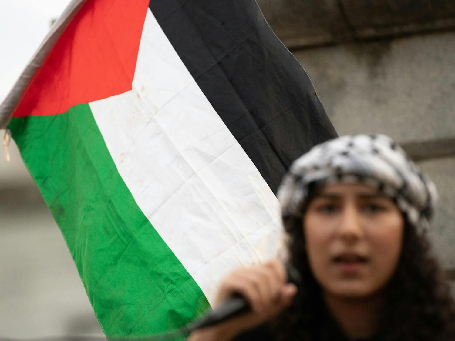 Sadeen Sarhan, a speaker at the Free Palestine Emergency Demonstration, stands in front of a Palestinian flag as she speaks to protestors gathered in front of the Statehouse in Columbia, S.C. The rally was held by the North and South Carolina Party for Social Liberation on Oct. 17, 2023.