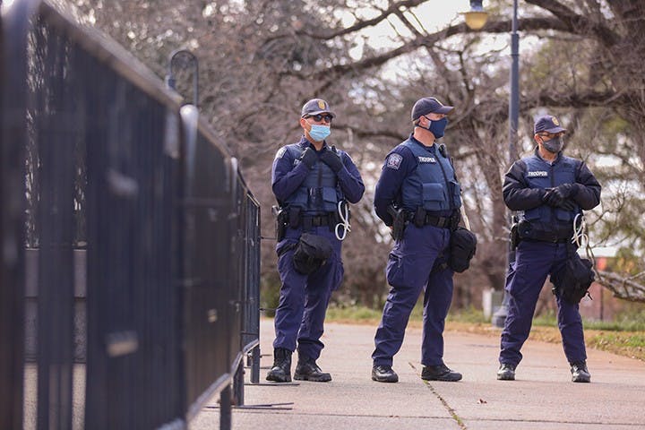 Three South Carolina highway patrol officers stand outside the fence that circled the perimeter of the Statehouse. Police presence increased significantly as the protest went on.&nbsp;