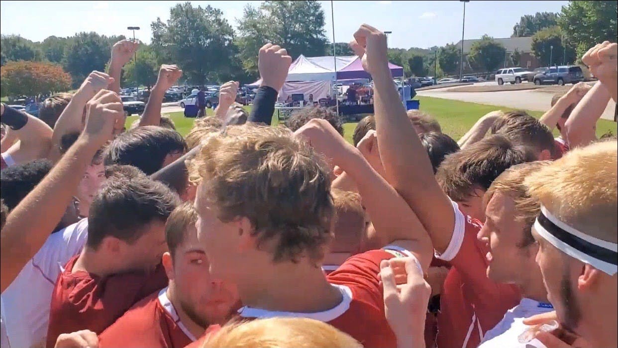 Members of the Gamecock club rugby team stand with their fists in the air.