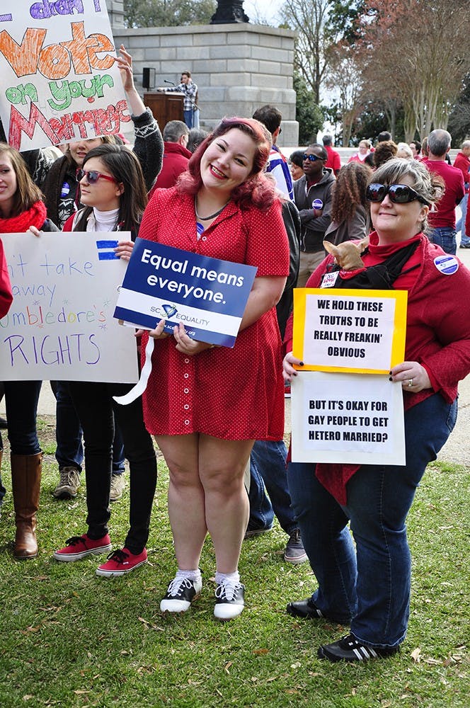 Second-year international studies student Tori Moore holds an "Equal means everyone" at a rally on Statehouse grounds Tuesday.