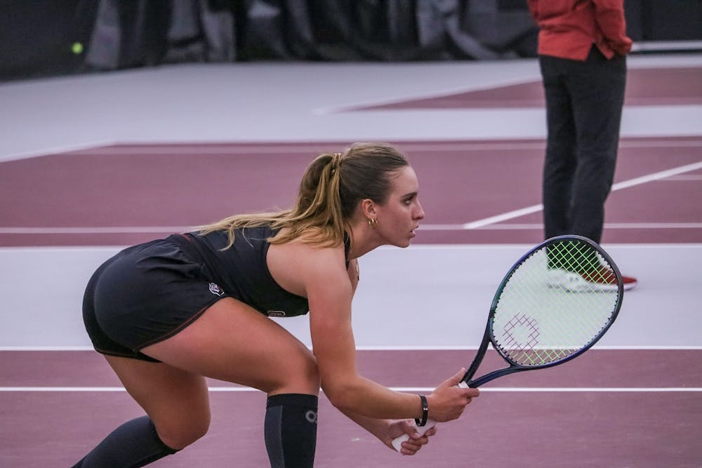 <p>Senior Ana Cruz lowers her stance as her partner, junior Allie Gretkowski, powers up for a strong serve against Yale on Feb. 17, 2023. The duo defeated the Bulldogs 6-2 in their set.&nbsp;</p>