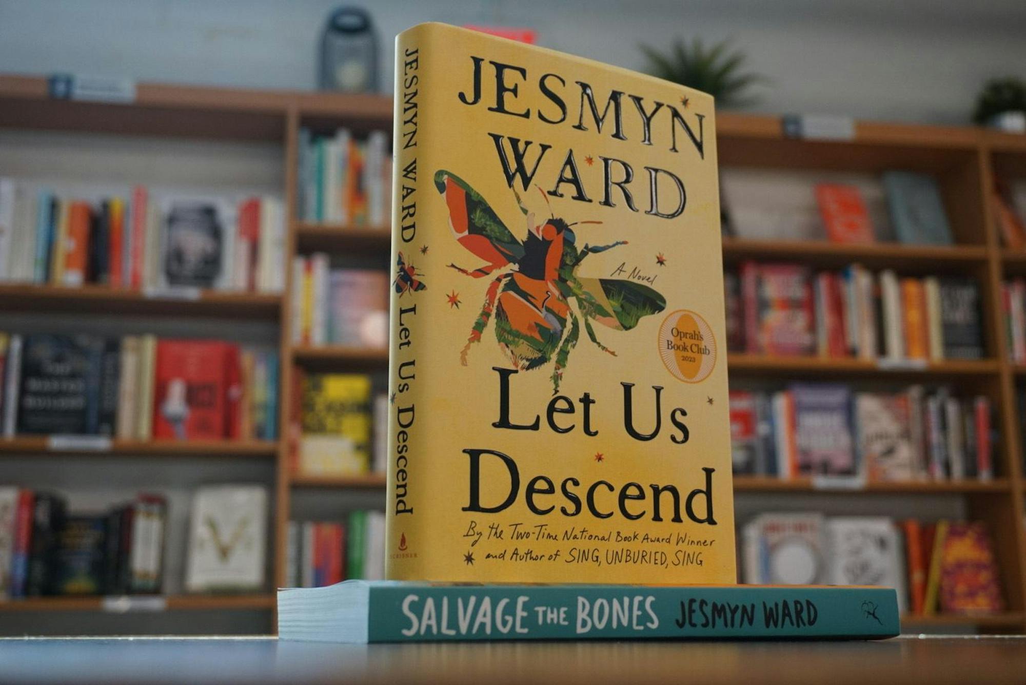 The bright yellow cover of Jesmyn Ward’s novel, 'Let Us Descend,' is on display at All Good Books bookstore, surrounded by many books of a similar genre. 