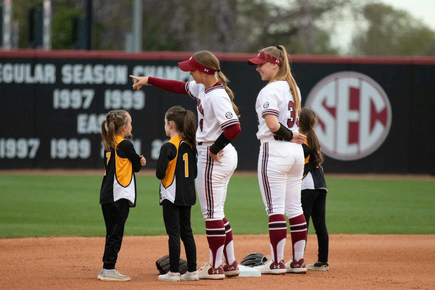 Junior infielder Brooke Blankenship (left) and freshman infielder Karley Shelton (right) stand on the field with members of a junior softball team before a game on March 23, 2024. South Carolina is 22-9 on the season.