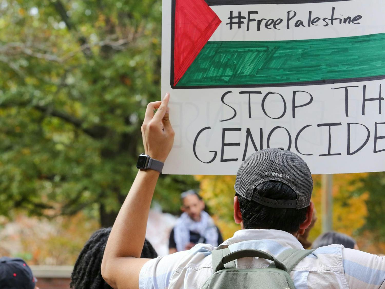 An attendee holds a sign saying "STOP THE GENOCIDE" at a walkout for Palestine event on the Russell House Patio on Nov. 9, 2023. Multiple students, faculty and staff carried signs, which they held while chanting "Free Palestine."