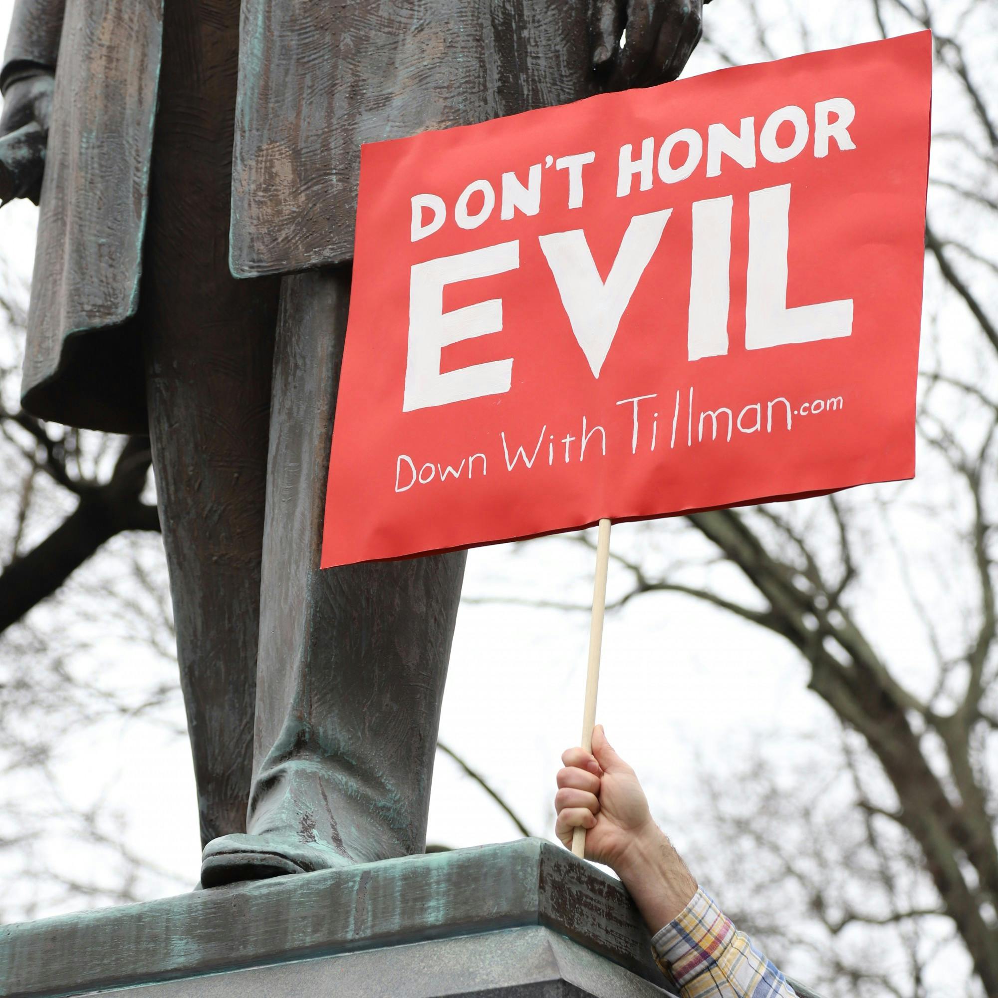A protestor holds  a sign that says  “DON’T HONOR EVIL, Down with Tillman” in front of the Benjamin Tillman statue on Tuesday January 12, 2021.