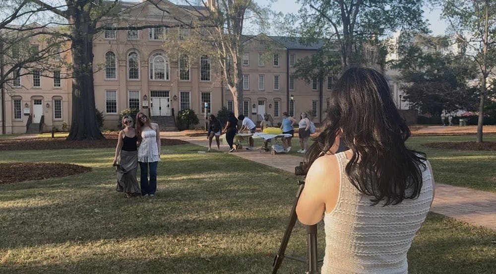 <p>Third-year visual communications student Grayson Edwards photographs fourth-year retailing students Caroline Kelly (left) and Regan Dowdy (right) for the Sustainability Photoshoot hosted by Fashion Board and Sustainable Carolina on March 23, 2026.</p>