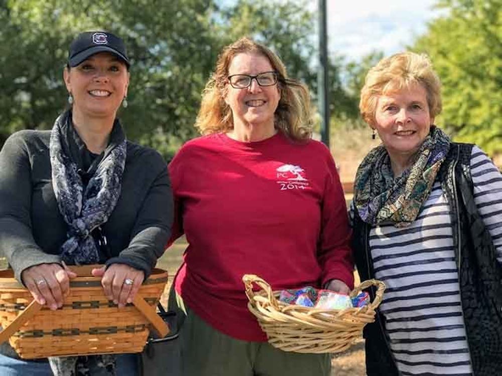 Ask a Mom team members Barbara Tiller, Elise Hane and Rhonda Filiatreault. Tiller and Hane hold baskets filled with cookies to give to students.