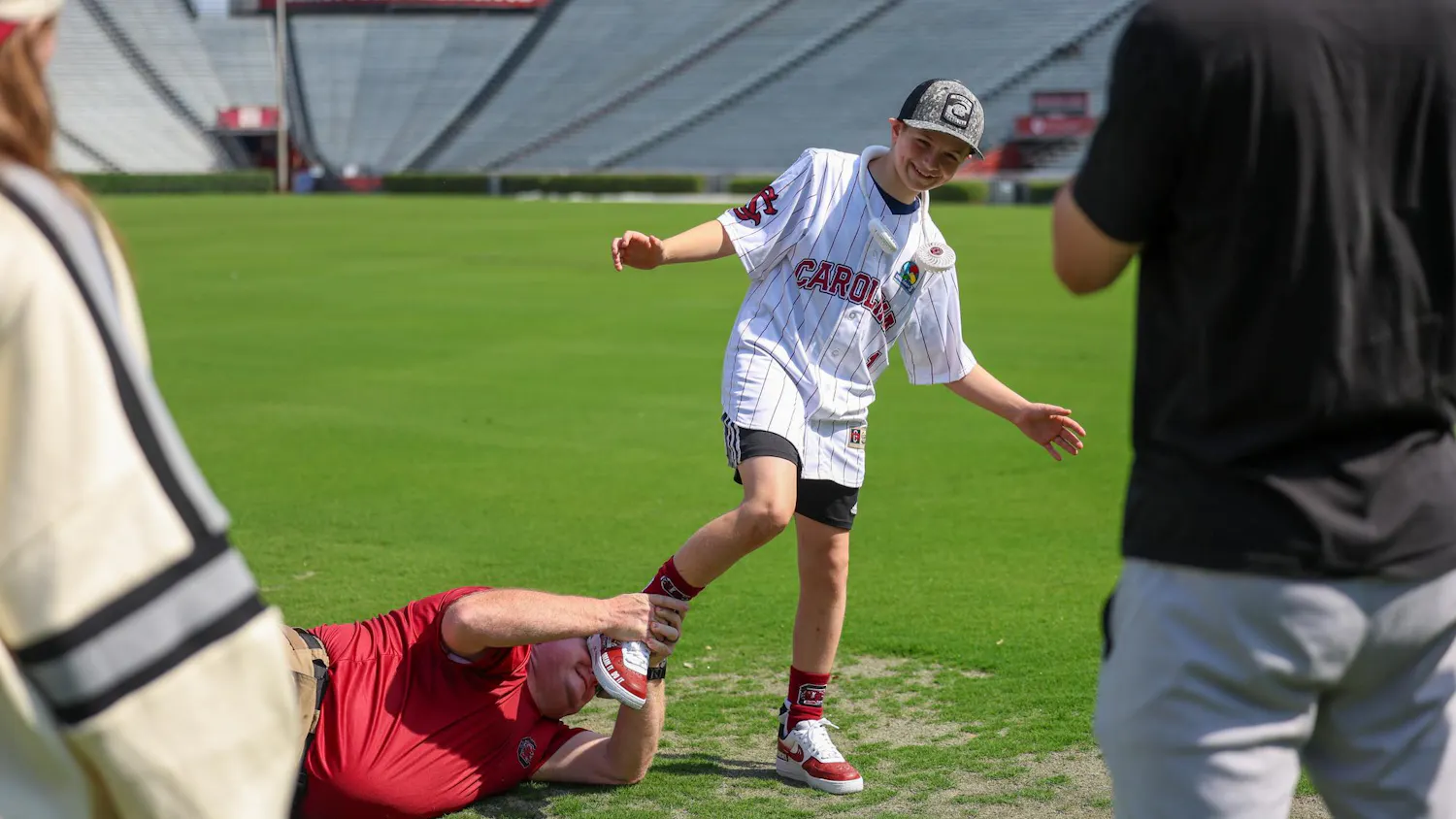 Lexington resident Gabriel Lyons is play-tackled by his dad while touring the fields at Williams-Brice Stadium on April 25, 2026. Lyons and his family toured the stadium and other athletics venues before Gabriel threw the first pitch at the baseball game between USC and Kentucky.