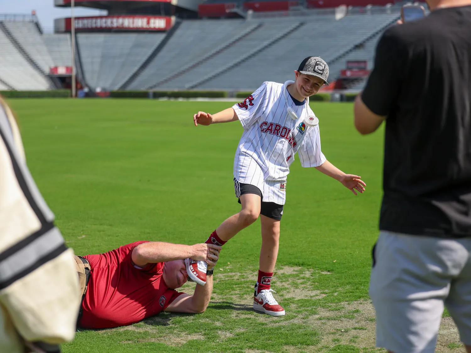 Lexington resident Gabriel Lyons is play-tackled by his dad while touring the fields at Williams-Brice Stadium on April 25, 2026. Lyons and his family toured the stadium and other athletics venues before Gabriel threw the first pitch at the baseball game between USC and Kentucky.