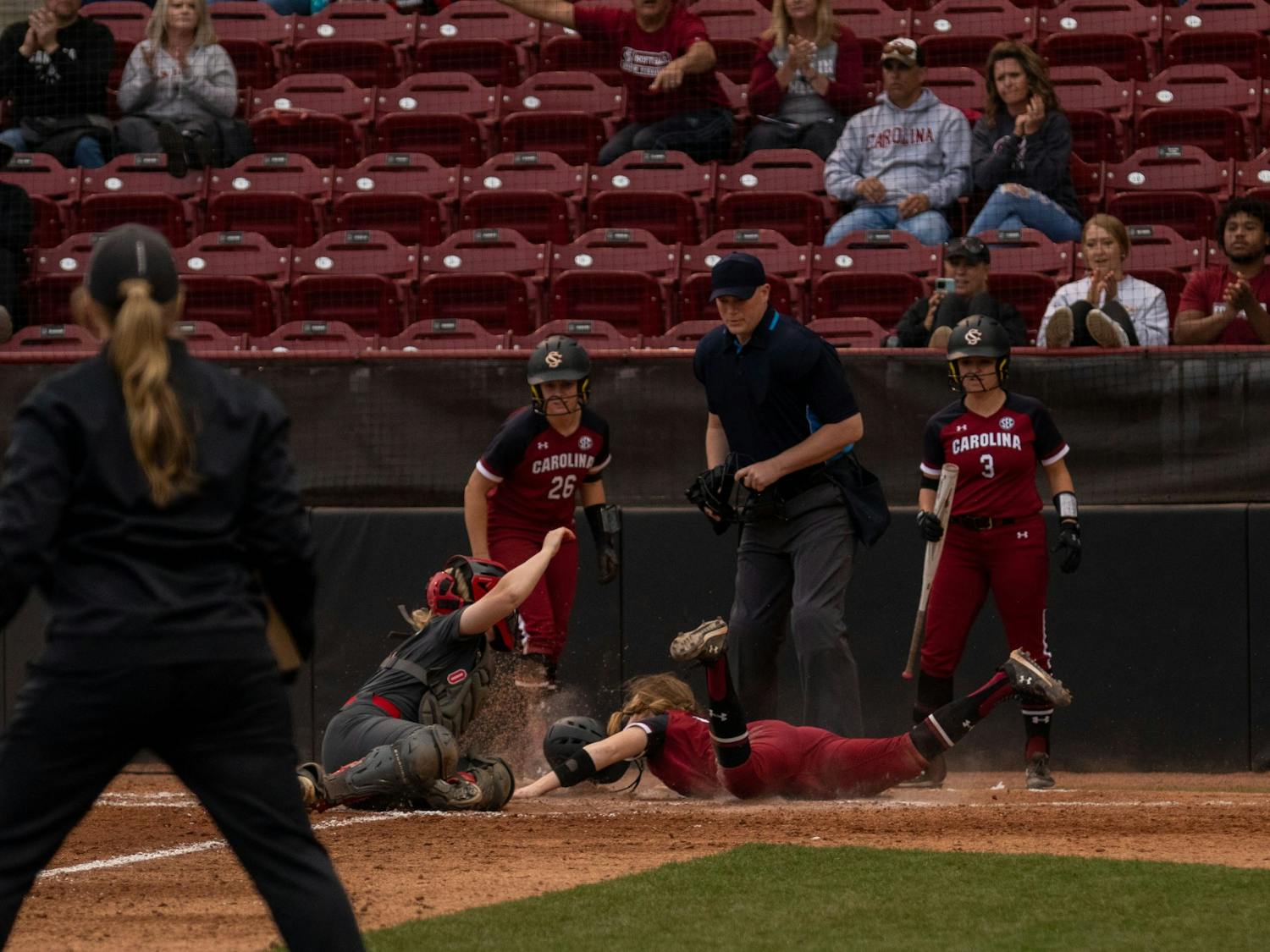 Freshmen Emma Sellers, crashes into umpire in an attempt to beat the ball to home plate in the fifth inning against Ohio State on Feb. 26, 2022, at Beckham Field. Carolina lost in their third game of the Carolina Classic against Ohio State 6-2. 