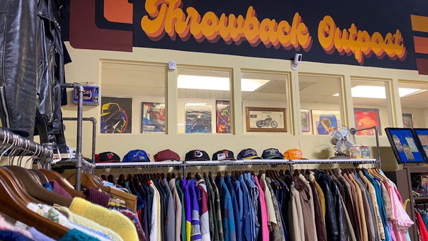 A rack of vintage clothes sit in front of a sign painted by Nicolette Bryan at Throwback Outpost on Feb. 7, 2023. The store, located on North Beltline Boulevard in Columbia, S.C., houses a plethora of vintage items from clothes, to records and even custom rugs.