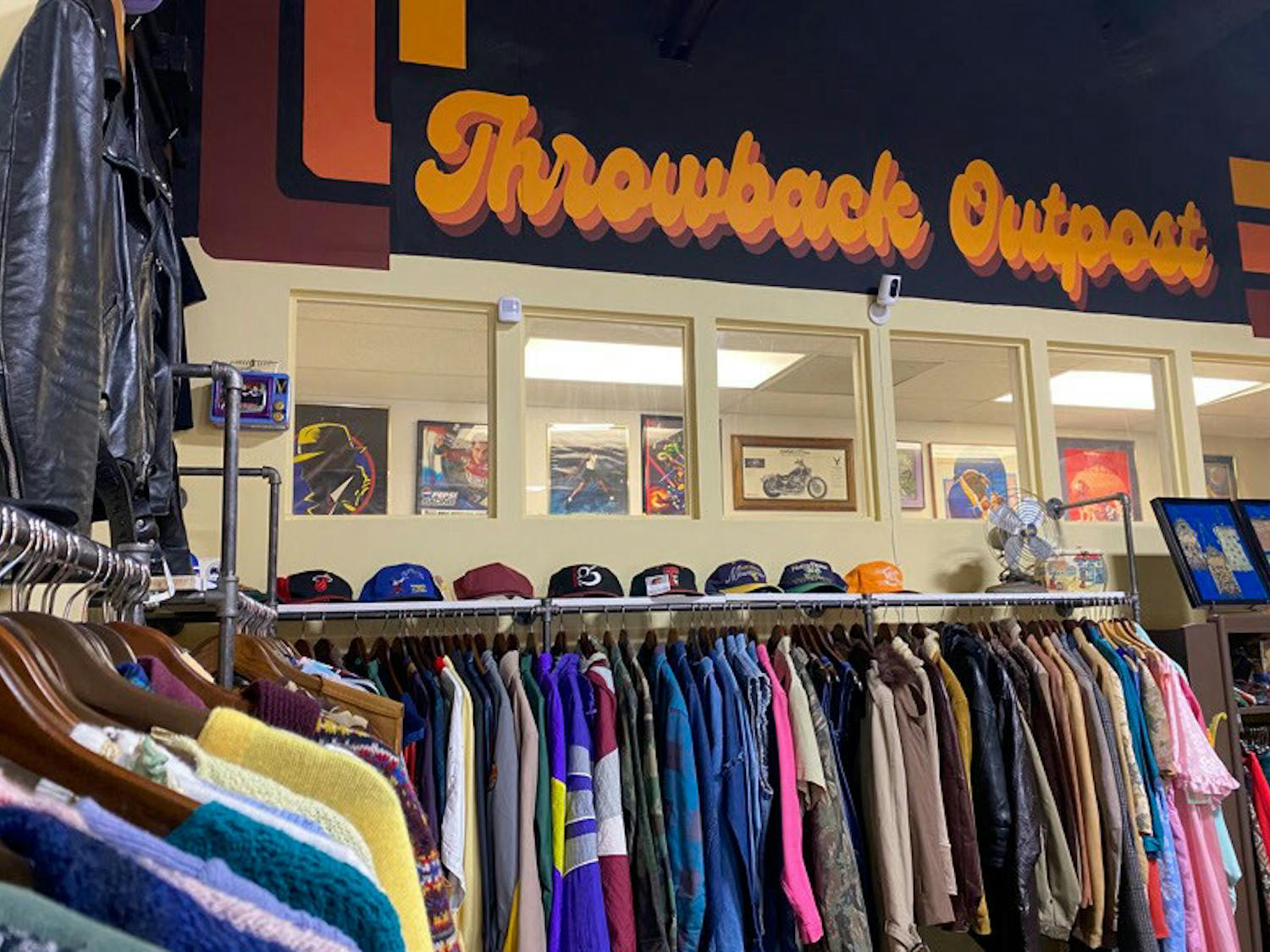 A rack of vintage clothes sit in front of a sign painted by Nicolette Bryan at Throwback Outpost on Feb. 7, 2023. The store, located on North Beltline Boulevard in Columbia, S.C., houses a plethora of vintage items from clothes, to records and even custom rugs.