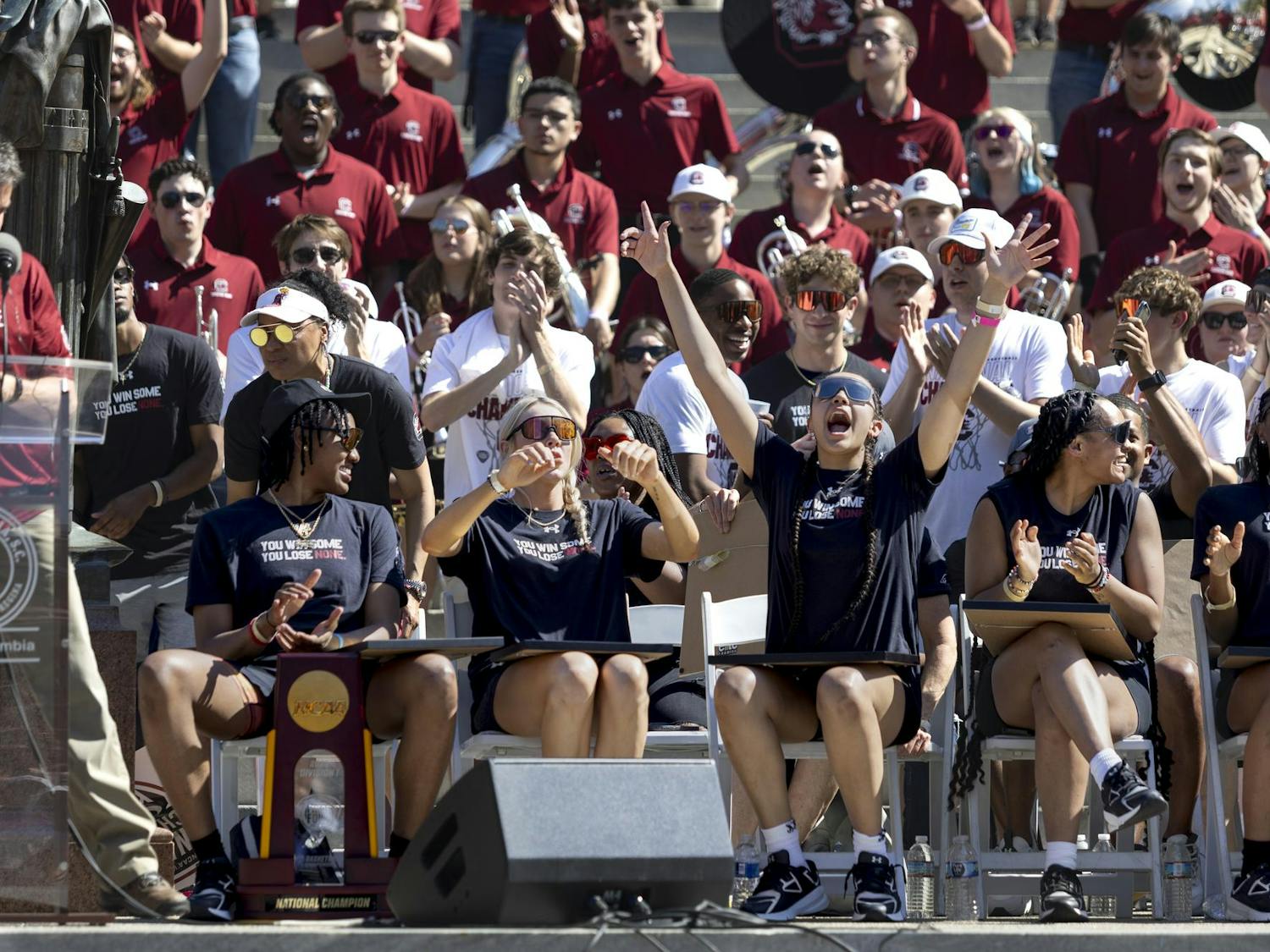Gamecock women's basketball players cheer for head coach Dawn Staley while sitting on the steps of the Statehouse on April 14, 2024. Columbia celebrated the team's undefeated national championship victory with a parade on Main Street.