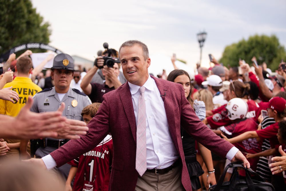 <p>FILE—Head football coach Shane Beamer high-fives fans while walking into Williams-Brice Stadium on Sept. 3, 2022. Beamer led his team to a 35-14 win against Georgia State.&nbsp;</p>
