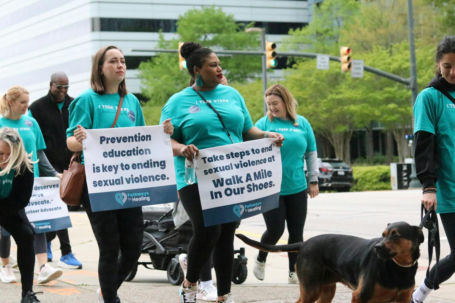 Two participants hold up a sign walking down the street for the Pathways to Healing walk on April 1, 2023. Columbia community members gathered at the Statehouse on Saturday to walk a mile in support of sexual assault survivors.