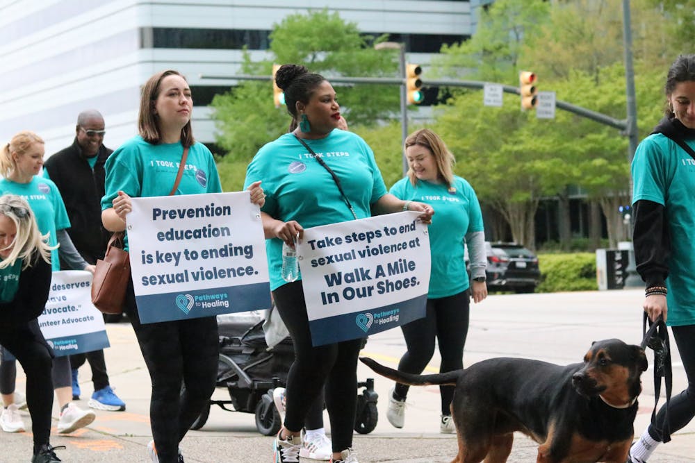 <p>Two participants hold up a sign walking down the street for the Pathways to Healing walk on April 1, 2023. Columbia community members gathered at the Statehouse on Saturday to walk a mile in support of sexual assault survivors.</p>