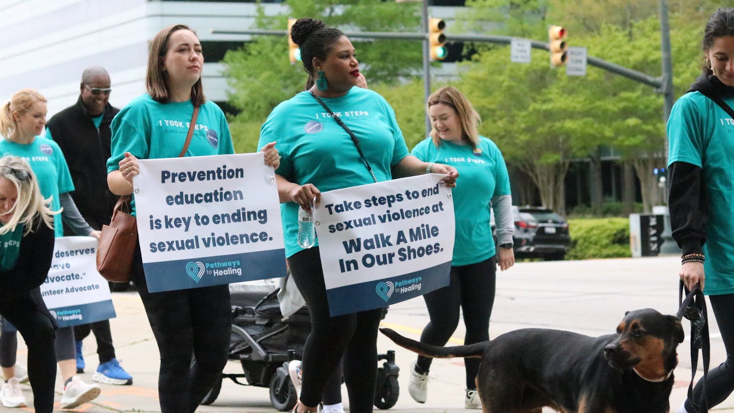 Two participants hold up a sign walking down the street for the Pathways to Healing walk on April 1, 2023. Columbia community members gathered at the Statehouse on Saturday to walk a mile in support of sexual assault survivors.